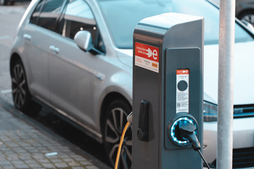 Een afbeelding van een man die zijn elektrische auto oplaadt aan het tankstation