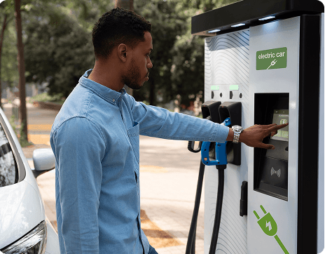 Een afbeelding van een man die zijn elektrische auto oplaadt aan het tankstation